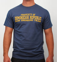 Indigo blue t-shirt with yellow text ‘Property of Dominican Republic Rum Drinking Team’ on a plain background by Hot Penguin, Ltd.